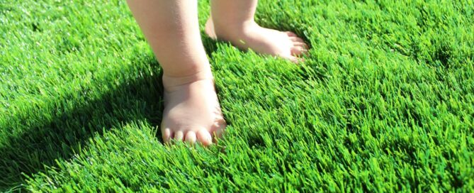 Premium Grass Blades Synthetic Artificial Turf: Baby Standing in Soft Lush turf