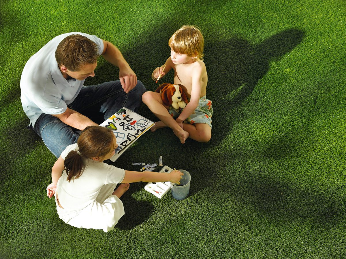 artificial-grass-playgrass Family painting activity on bright green synthetic grass. Dad and children sitting on artificial turf outdoors.